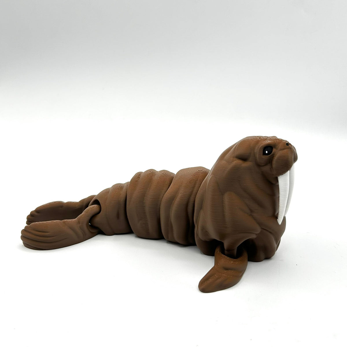 A brown walrus 3D Printed toy with white tusks, posed on a seamless white studio background.
