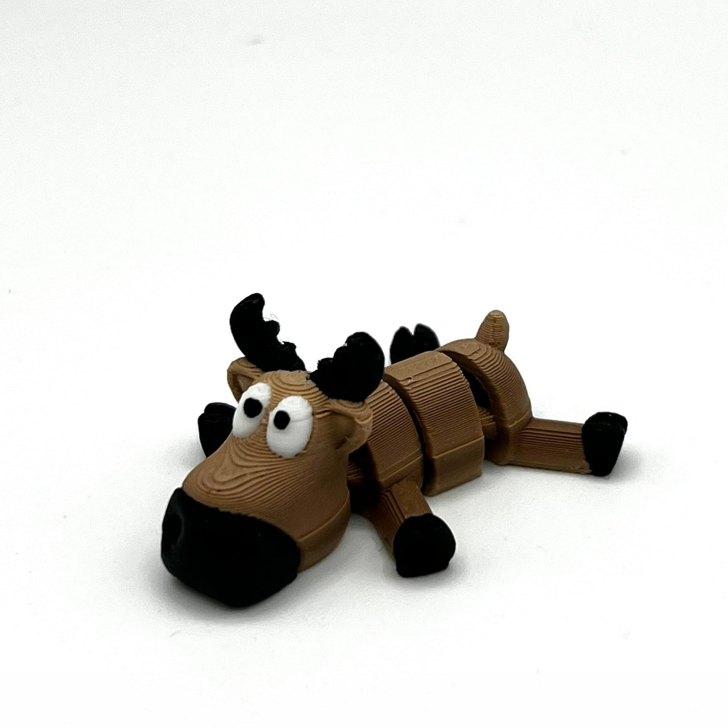 A small brown reindeer figurine with black antlers, black hooves, and large white eyes, photographed on a plain white background.